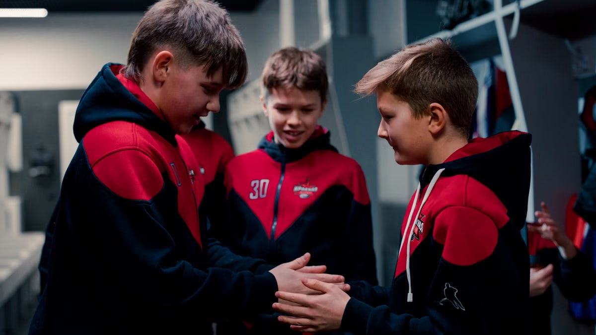 Teen hockey players in a locker room sharing a moment of team spirit.